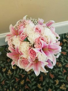 a bouquet of pink and white flowers sitting on the floor in front of a wall