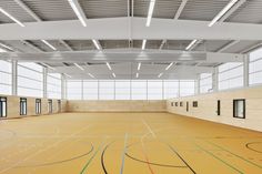 an indoor basketball court with yellow and green lines on the floor, surrounded by large windows