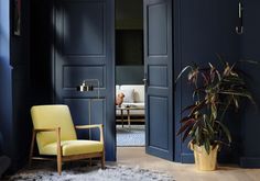 a living room with blue walls and a yellow chair next to a potted plant