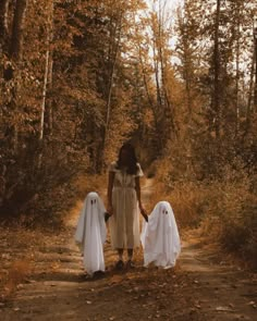 two people dressed in ghost costumes walking down a dirt road