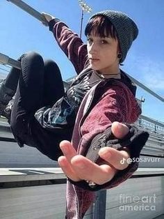 a young boy is hanging upside down on a metal pole with his hands outstretched in the air