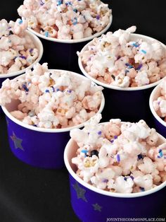 four purple cups filled with white and blue popcorn