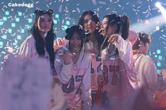 group of young women standing together in front of confetti