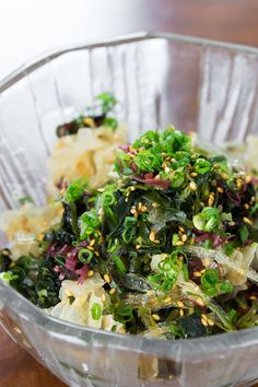 a glass bowl filled with food on top of a wooden table