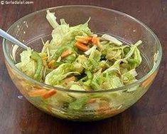 a bowl filled with lettuce and carrots on top of a wooden table