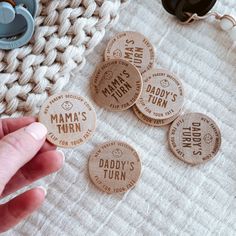 a person is pointing to some wooden badges on a white blanket with other items nearby