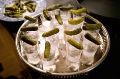 several glasses with pickles in them are sitting on a tray next to another plate