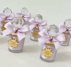 four small glass jars with purple bows and crystal balls on them, each containing a sun