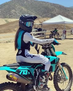 a woman riding on the back of a dirt bike