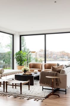 a living room filled with furniture and lots of large glass doors that look out onto the outdoors