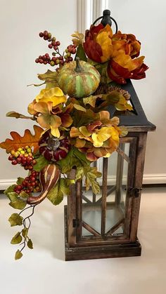 a lantern filled with flowers and leaves on top of a table