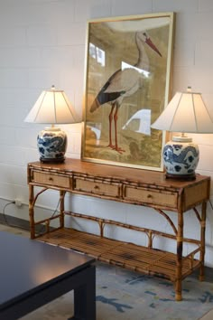 a table with two lamps and a painting on the wall behind it in a living room