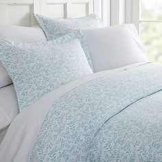 a bed with white sheets and blue pillows