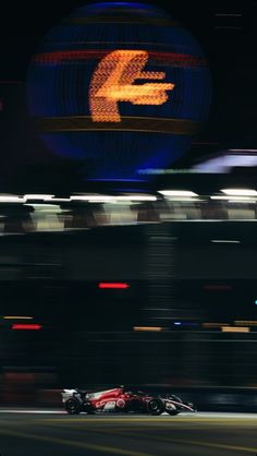 a man driving a racing car on a track at night with motion blurry in the background