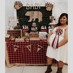 a pregnant woman standing in front of a baby shower table