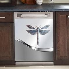 a dishwasher with a blue dragonfly on it's side in a kitchen