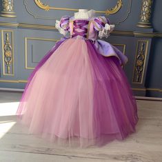 a pink and purple dress sitting on top of a wooden floor