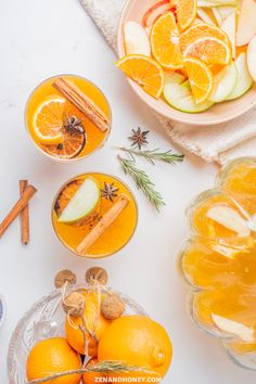 oranges, apples and cinnamon sticks are arranged in bowls on a white counter top