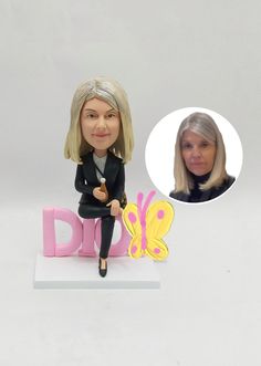 a custom bobble head doll sitting on top of a pink and yellow sign with a woman's profile next to it