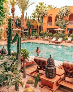 a woman in a pool surrounded by chairs and cacti with palm trees around it