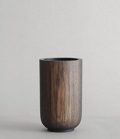 a wooden cup sitting on top of a white table next to a gray wall and floor