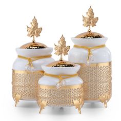 three white vases with gold leaf decorations on them