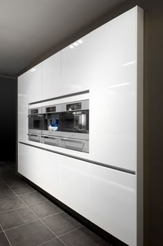 a modern kitchen with white cabinets and black tile flooring, including an oven built into the wall