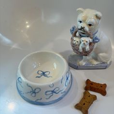 a ceramic dog bowl with two small dogs in it and a bone shaped dish next to it