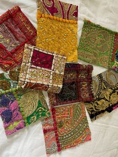 many different types of cloths are laid out on a white tablecloth with gold, red and green designs