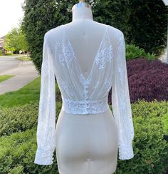 a mannequin wearing a white dress with long sleeves and lace on the back