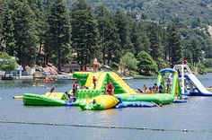 an inflatable water park on the lake with people playing and swimming around it