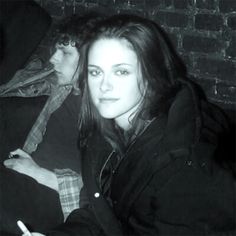 two people sitting next to each other in front of a brick wall