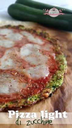 a pizza sitting on top of a wooden cutting board next to a cucumber