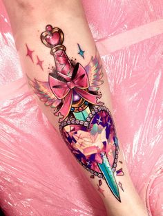 a woman's leg with a pink bow and dagger tattoo on her left calf