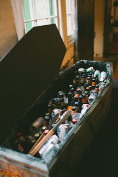 an open chest full of beer bottles in a room with wooden flooring and windows