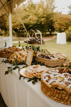 a table filled with lots of food on top of a white tablecloth covered field