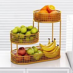 two tiered baskets filled with fruit sitting on top of a white counter next to a microwave