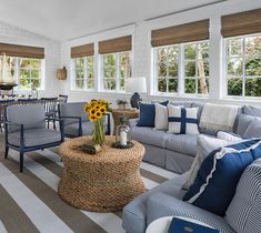 a living room filled with lots of furniture next to a window covered in blinds and sunflowers