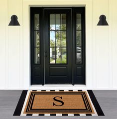 a door mat with the letter s on it in front of a black and white house