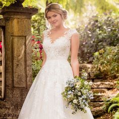 a woman in a wedding dress holding a bouquet and posing for the camera with her hand on her hip