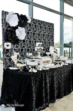 a table with black and white decorations in front of a large glass window at an event