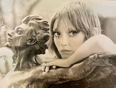 a black and white photo of a woman hugging a statue