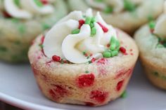 some cupcakes with white frosting and sprinkles on a plate