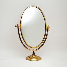 a gold colored mirror on a stand against a white background