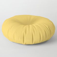 a yellow round pillow sitting on top of a white floor