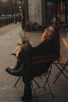 a woman sitting in a chair on the sidewalk