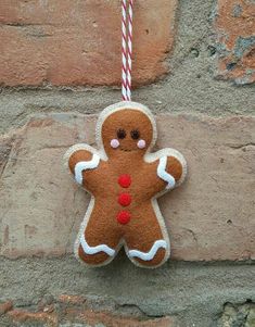 a ginger ornament hanging on a brick wall with a red and white striped cord