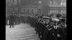 a group of men in suits and hats marching down the street with flags on their heads