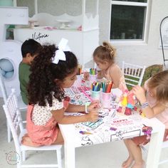 several children sitting at a table with markers and pens