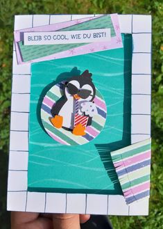 a hand holding up a card with a penguin on it's face and the words bleib so cool we du bist